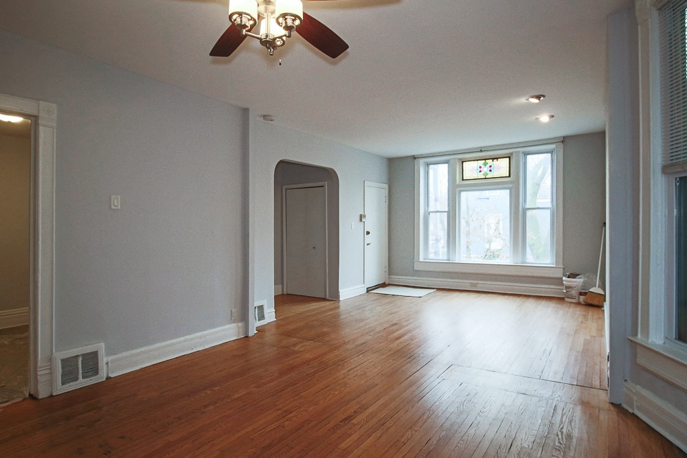 an empty living room with wood floors and a ceiling fan